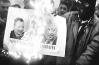 Un palestino enmascarado quema las imágenes de los candidatos israelíes.